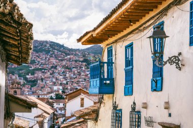 Geleneksel bir sömürge binası, mavi ahşap balkonları ve Cusco 'da yamaç manzarası var..