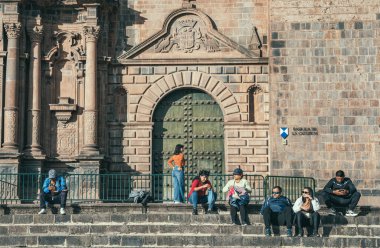Cusco, Peru - 20 Mart 2025: Turistler ve yerel halk Plaza de Armas.l 'daki Tarihi Cusco Katedrali basamaklarında oturuyor ve yürüyor.