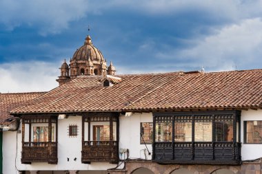 Cusco 'nun tarihi merkezinde geleneksel bir İspanyol sömürge binasının ön yüzü ve arka planda bir kilise kubbesi..