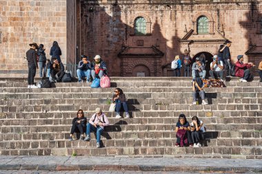 Cusco, Peru - 20 Mart 2025: Turistler ve yerel halk Plaza de Armas.l 'daki Tarihi Cusco Katedrali basamaklarında oturuyor ve yürüyor.