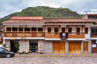 Pisac, Peru - 20 Mart 2025: Kutsal Vadi 'deki Pisac Meydanı' nda (Plaza Constitucion) geleneksel ahşap balkonlu renkli koloni binaları