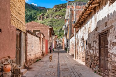 Pisac, Peru - 20 Mart 2025: Pisac kasabasındaki büyüleyici bir sokakta dinlenen turistler ve yerel halk