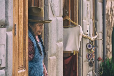 Pisac, Peru - 20 Mart 2025: Pisac kasabasında geleneksel Andean kıyafetleri ve şapkası giyen otantik yerli bir kadının portresi.