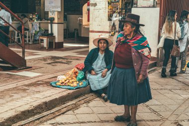 Pisac, Peru - 20 Mart 2025: Pisac kasabasında renkli geleneksel giysiler giyen iki yerli kadının sahnesi