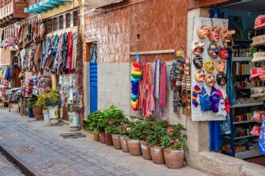 Pisac, Peru - 20 Mart 2025: Pisac kasabasının dar sokaklarında geleneksel giysi ve hediyelik eşya dükkanları