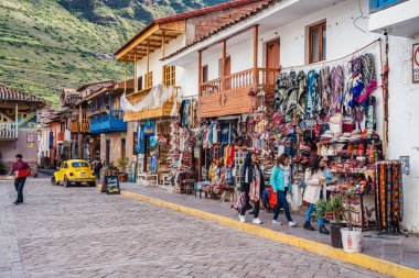 Pisac, Peru - 20 Mart 2025: Pisac şehir meydanındaki (Plaza Constitucion) geleneksel giysi ve hediyelik eşya dükkanları