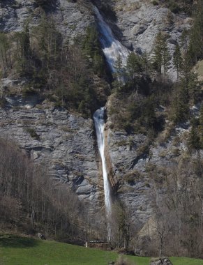Dundelbachfall şelalesi ve Lungern, İsviçre yakınlarında yeşil tepeler ve ağaçlar.