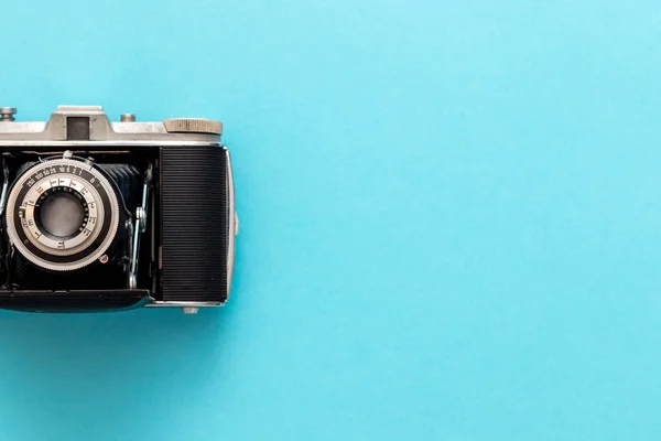 Old retro camera seen from top view in flat lay against blue pastel showing nostalgic feeling.