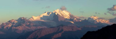 Güneş doğarken karla kaplı dağların nefes kesici güzelliğini tecrübe edin. Sıcak ışık, engebeli tepeler ve sakin manzaralara altın bir parıltı saçar. Macera ve merak hissi uyandırır..