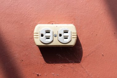 Guatemala elektrik prizi, dramatik gölgelerle dolu kırsal kırmızı bir duvara monte edilmişti. Endüstriyel cazibe ve minimalist dekor hissi uyandırıyordu.