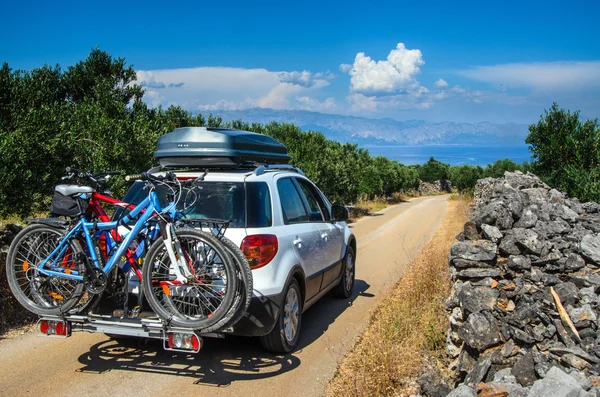 La carreteraCoche con techo y bicicleta en la carretera en un olivar en la isla mediterránea de Hvar en Croacia en un olivar en la isla mediterránea de Hvar en Croacia —  Fotos de Stock