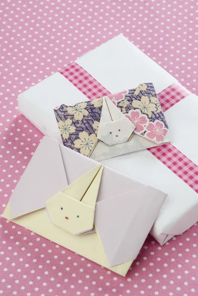 Sobres de conejo en origami con una caja de regalo sobre fondo rosa con — Foto de Stock