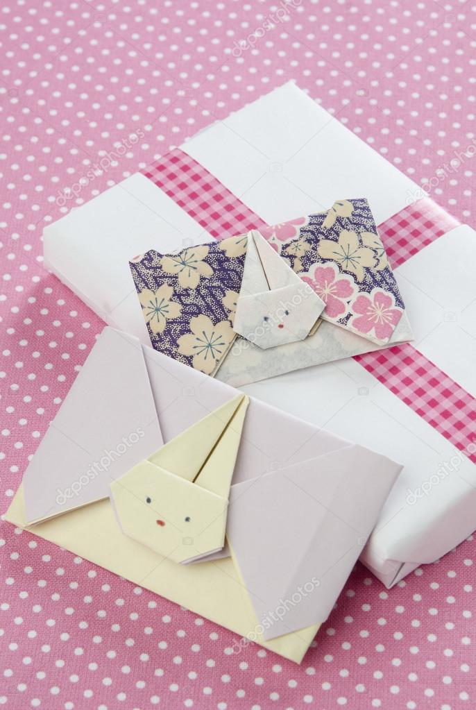 envelopes origami rabbit with a gift box on pink background with