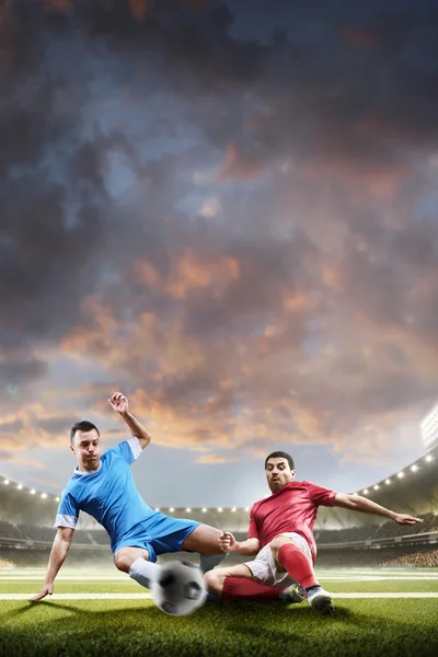 Jogadores de futebol em ação no fundo do estádio por do sol — Fotografia de Stock