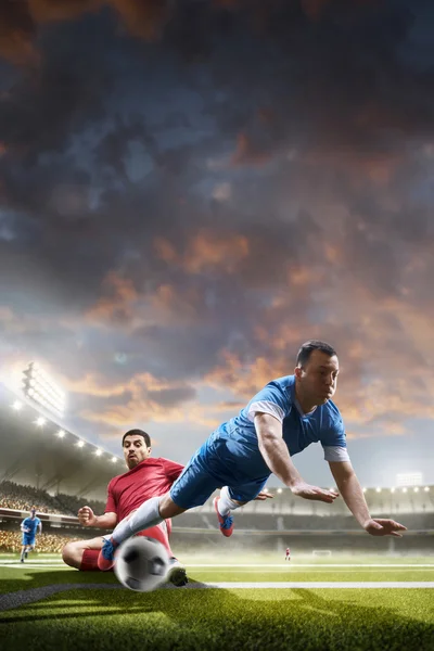 Jogadores de futebol em ação no fundo do estádio por do sol — Fotografia de Stock