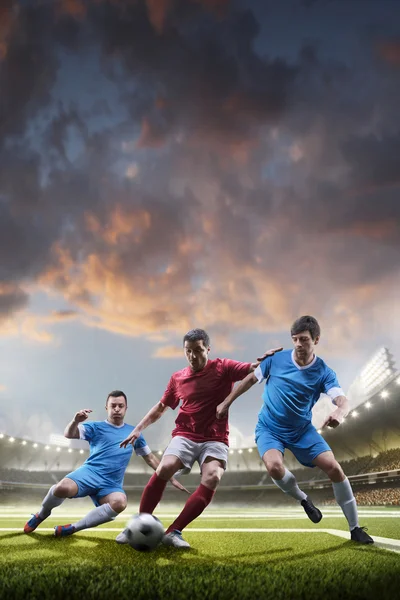 Jogadores de futebol em ação no fundo do estádio por do sol — Fotografia de Stock