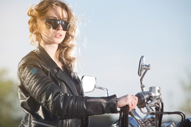 Motorcu kız batımını bir motosiklet üzerinde deri ceketli.