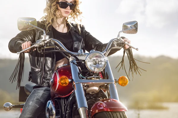 Bikermädchen in Lederjacke auf einem Motorrad beim Blick auf den Sonnenuntergang. — Stockfoto