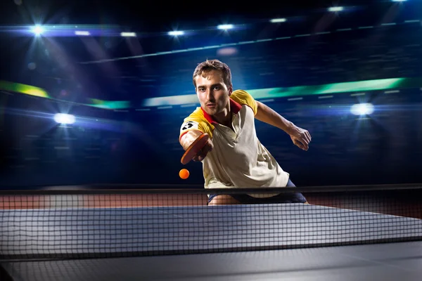 Young sports man tennis player playing on black background with lights — Stock Photo, Image