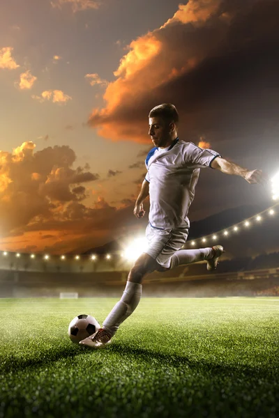 Joueur de football en action sur fond de stade au coucher du soleil — Photo