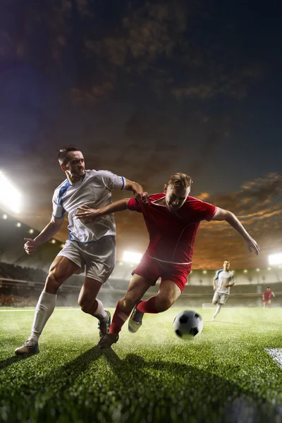 Fußballer in Aktion vor dem Hintergrund des Sonnenuntergangs im Stadion — Stockfoto