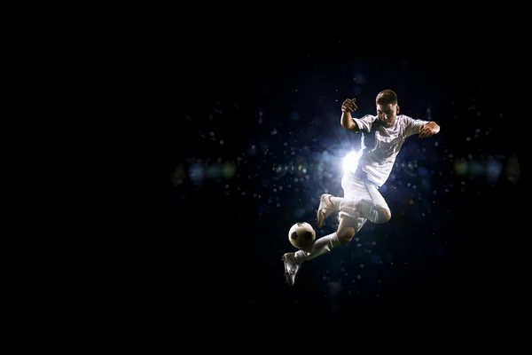 Fußballer in Aktion vor schwarzem Hintergrund — Stockfoto