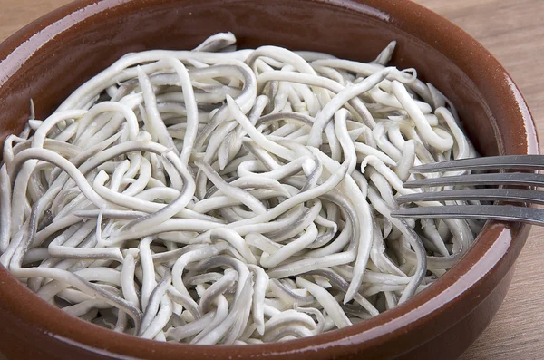 Earthenware bowl withyoung eels cooked with garlic Stock Picture