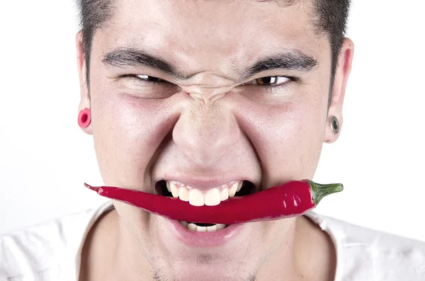 Hombre divirtiéndose, sosteniendo rojo picante pimienta en la boca . — Foto de Stock