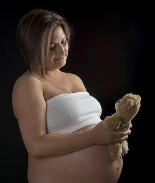 Moeder tijdens de zwangerschap houden een teddybeer — Stockfoto