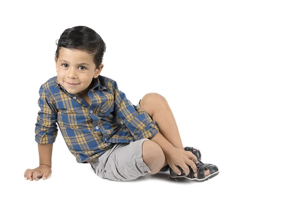 Ładny mały chłopiec siedzi na białym tle na białym tle. — Zdjęcie stockowe
