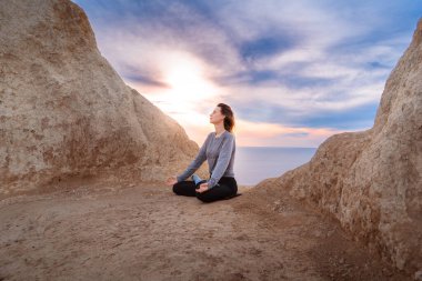Kadın gün doğumunda meditasyon yapıyor ve yoga yapıyor.