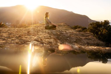 Nilüferde meditasyon yapan kadın gün doğumunda poz verir.