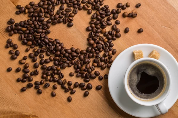 Coffee cup, sugar and coffee beans on wooden background. — Stock Photo, Image