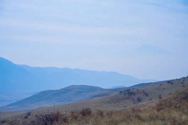 Winter cloudy landscape with Ararat mountain and field in foreground.