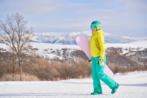 Mulher com snowboard contra fundo de montanhas — Fotografia de Stock