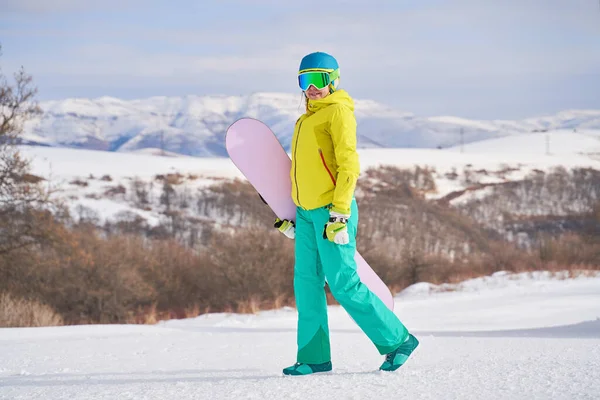 Vrouw met snowboard tegen de achtergrond van bergen — Stockfoto