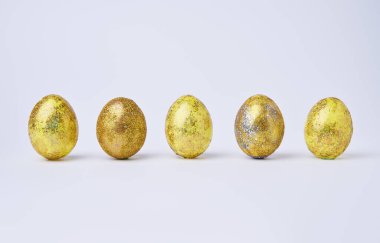 Beyaz arka planda altın renginde parlak yumurtalar.