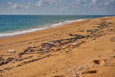 Plaja çöp döküldü. Kullanılmış kirli plastik şişeler, paketler ve diğer ev çöpleri..