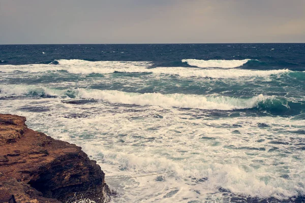 Las olas del mar chocan contra la costa rocosa —  Fotos de Stock