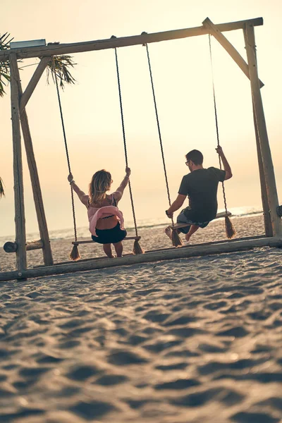 Jovem casal atraente balançando em seesaw na praia. — Fotografia de Stock