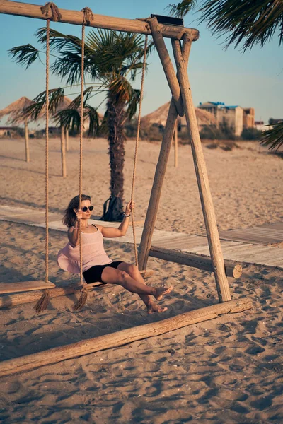 Jovem mulher atraente balançando em seesaw na praia. — Fotografia de Stock