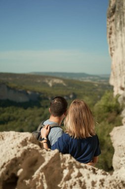 Çift bir kayanın üzerinde kalır, manzaraya bakar ve manzaranın ve temiz havanın tadını çıkarır..