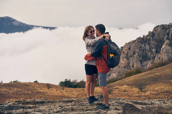 Casal é ficar sobre as pedras, descansando, admirando uns aos outros e a vista, apreciando o ar fresco. — Fotografia de Stock