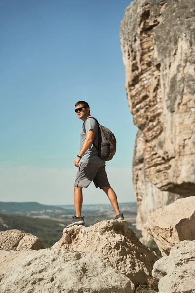 Jongeman verblijf op een rots, kijken naar het landschap en genieten van het uitzicht en frisse lucht. — Stockfoto