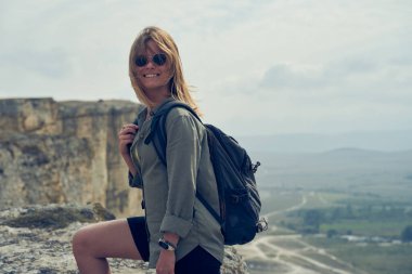 Kadın bir kayanın üzerinde durur, manzaraya bakar ve manzaranın ve temiz havanın tadını çıkarır..