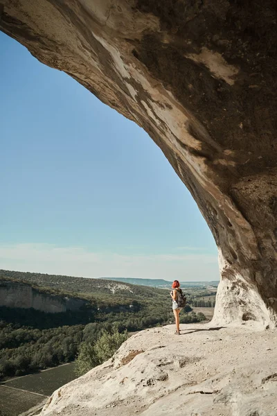 Une jeune femme reste sur un rocher, regardant le paysage et profitant de la vue et de l'air frais. — Photo