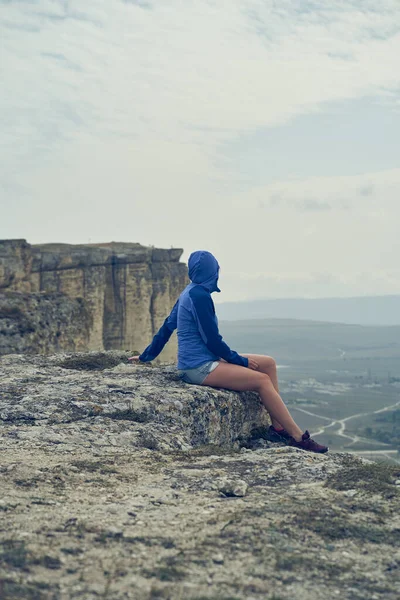 여자가 바위 위에 앉아 풍경을 보고 경치와 신선 한 공기를 즐긴다. — 스톡 사진