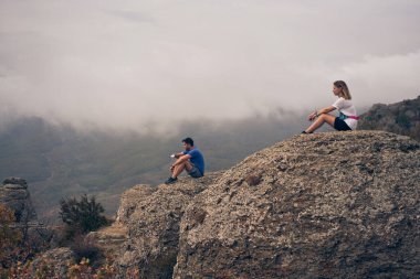 Çift bir kayanın üzerinde oturur, manzarayı seyreder ve manzaranın ve temiz havanın tadını çıkarır..