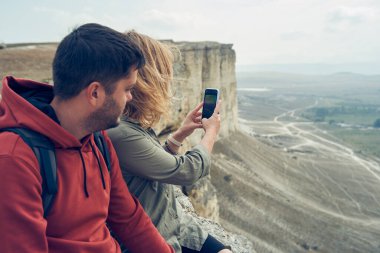Çift taşların üzerinde oturuyor, dinleniyor, fotoğraf çekiyor ve manzaranın ve temiz havanın tadını çıkarıyor..