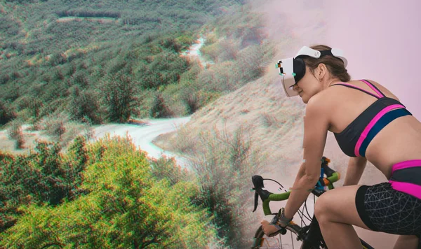Mulher treina em casa em uma bicicleta estacionária vestindo VR-fone de ouvido. — Fotografia de Stock